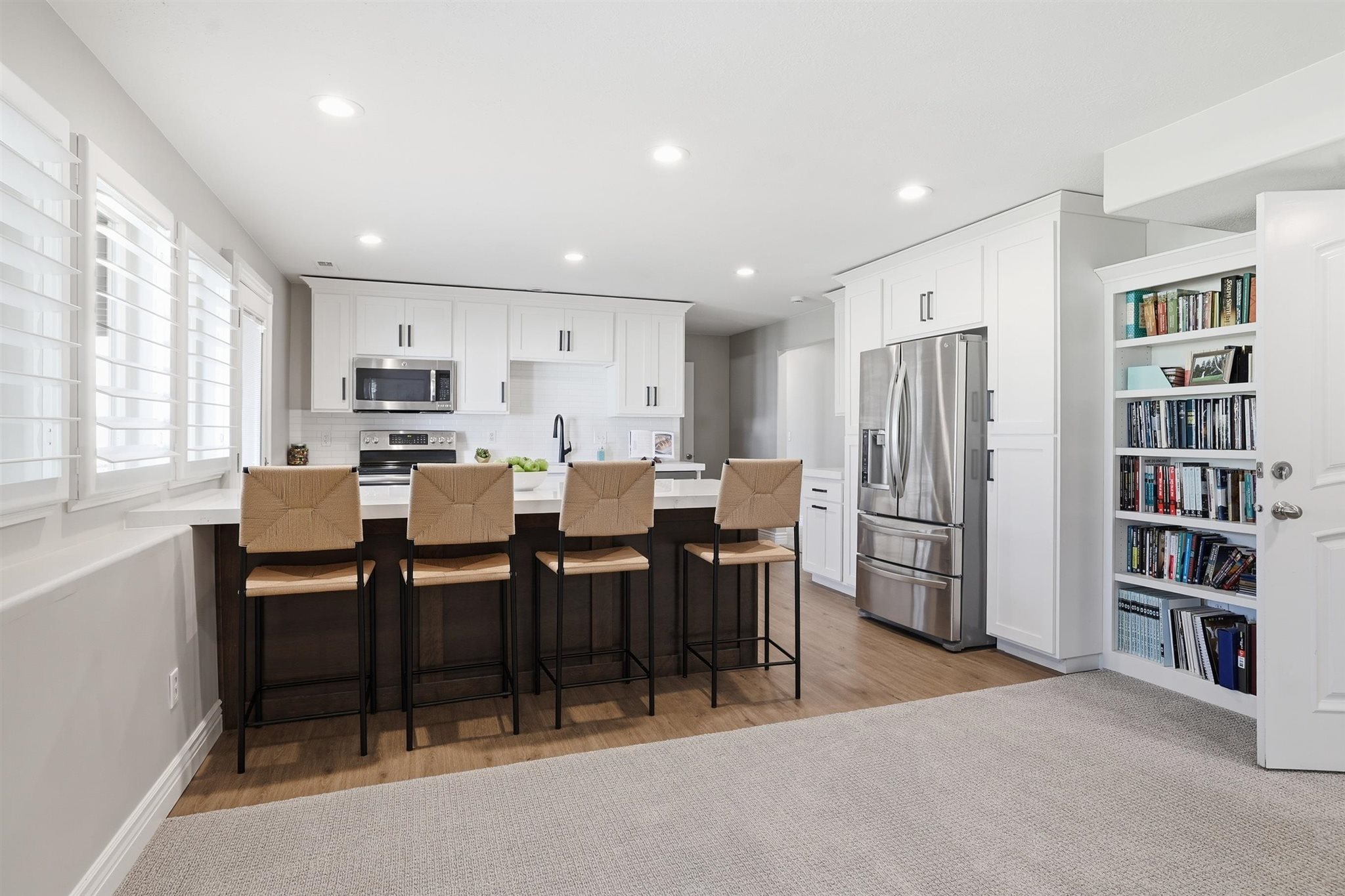 Modern kitchen featuring white cabinetry, stainless steel appliances, a center island with countertop seating, and recessed lighting
