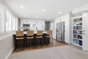 Modern kitchen featuring white cabinetry, stainless steel appliances, a center island with countertop seating, and recessed lighting