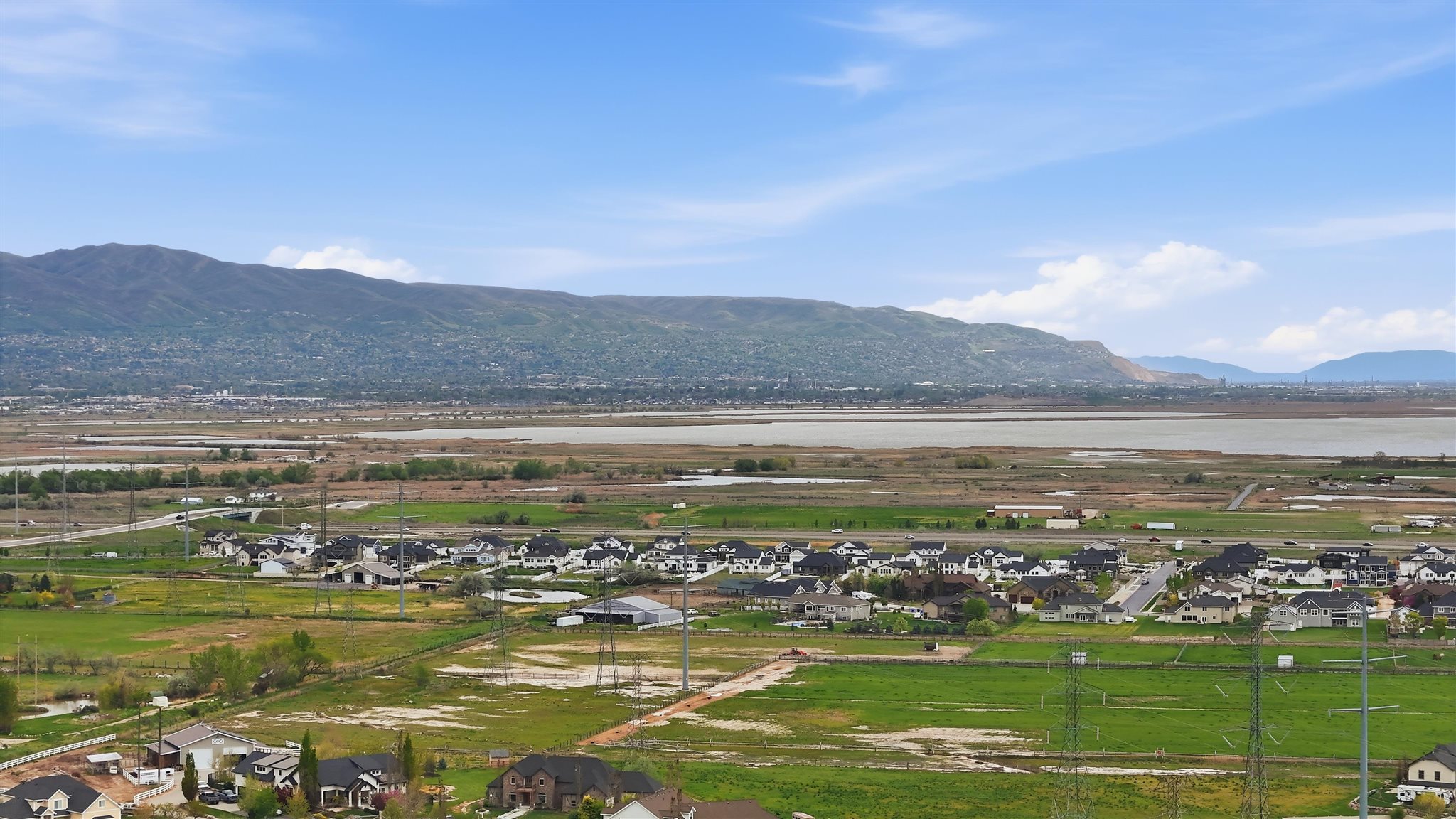 Expansive landscape featuring distant mountains, a body of water, and residential developments