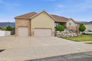 Stucco and brick facade residence with a two-car garage, expansive driveway, and stone accents