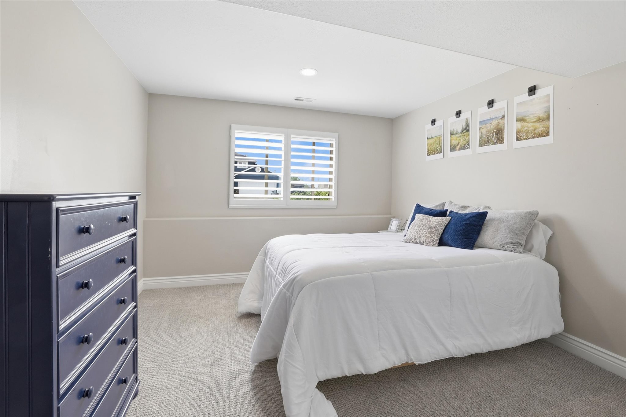 Carpeted room with a window featuring white plantation shutters