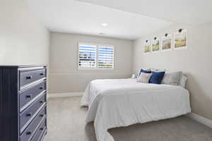 Carpeted room with a window featuring white plantation shutters