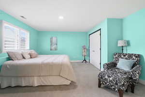 Carpeted room with a recessed light, dual windows with white plantation shutters, and a white bi-fold closet door