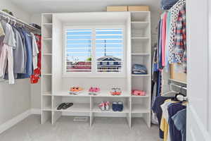 Integrated custom closet system with built-in shelving, hanging rods, and a central window featuring white plantation shutters