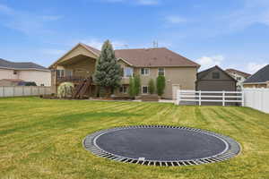 Expansive backyard with manicured lawn and mature trees, featuring a stucco exterior home with a two-story deck, a covered patio, and a detached shed