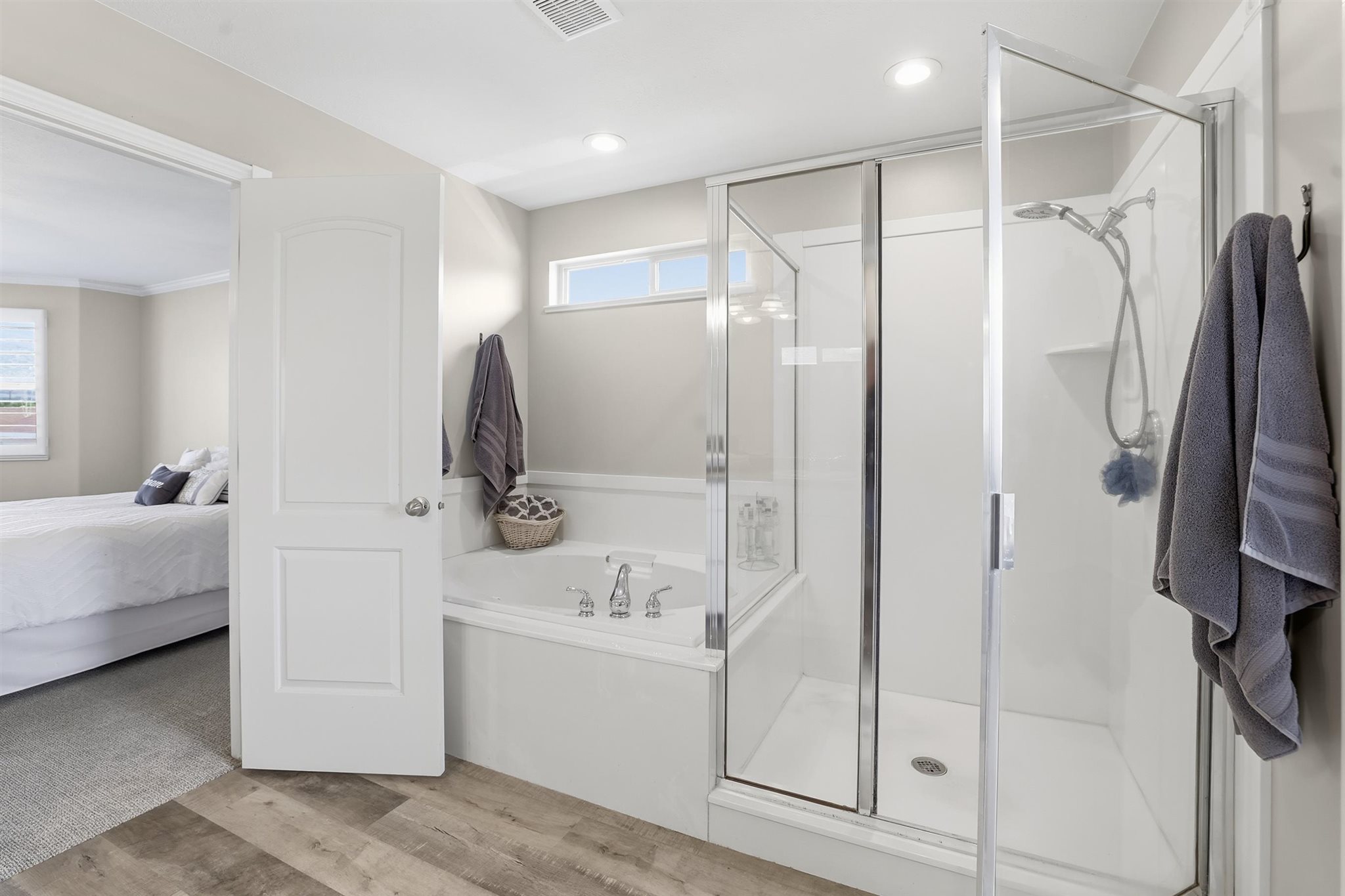 Bathroom featuring a glass-enclosed standing shower, a built-in tub with chrome fixtures, and wood-finish flooring