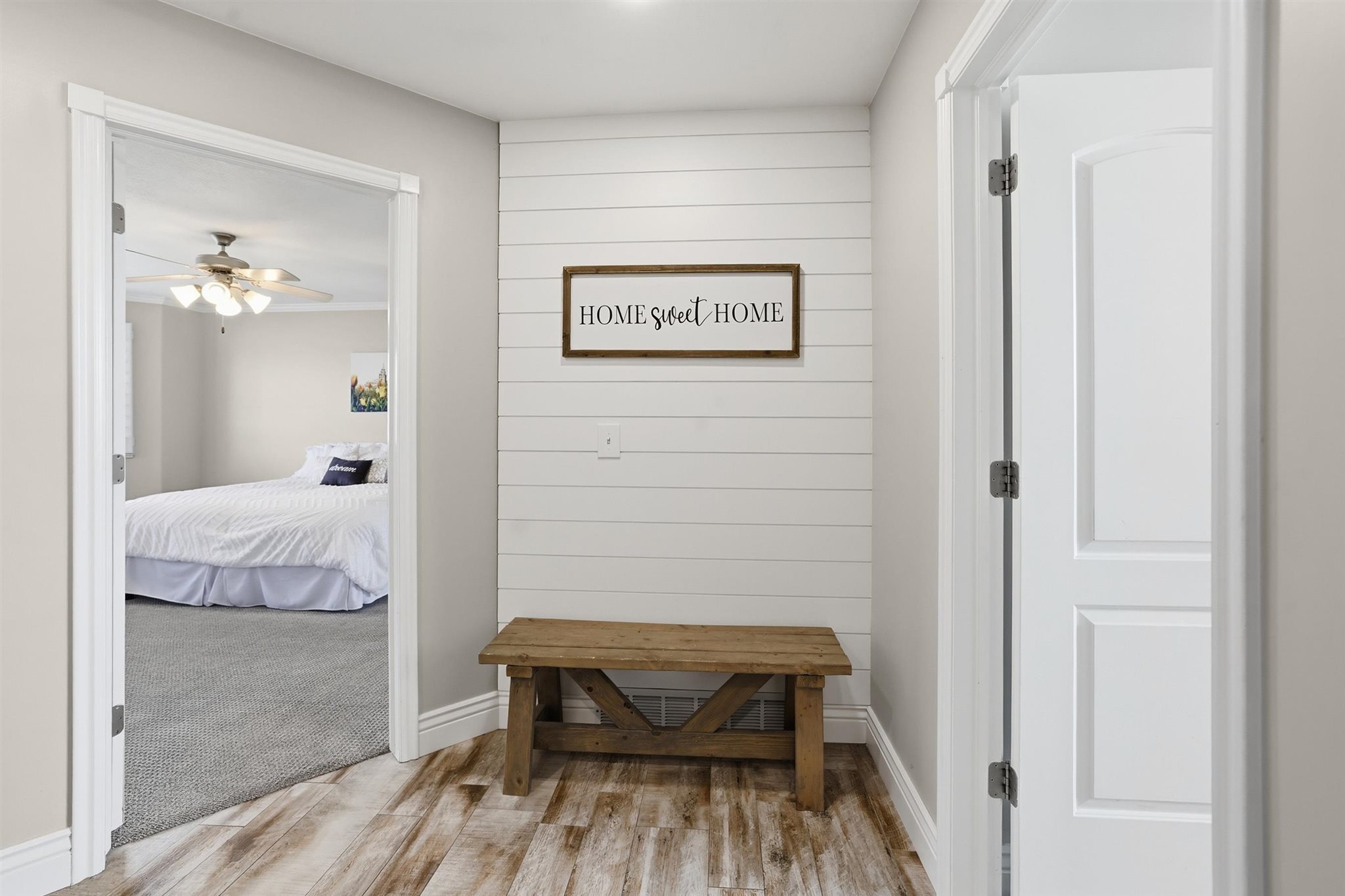 Inviting entryway featuring wood-finish flooring, a decorative shiplap accent wall, and a rustic wooden bench