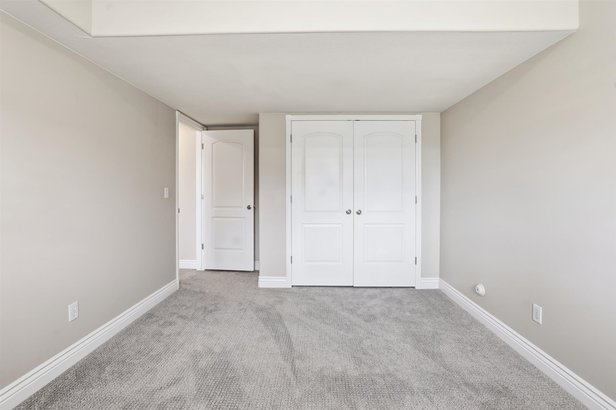 Neutral-toned walls complement plush grey carpeting