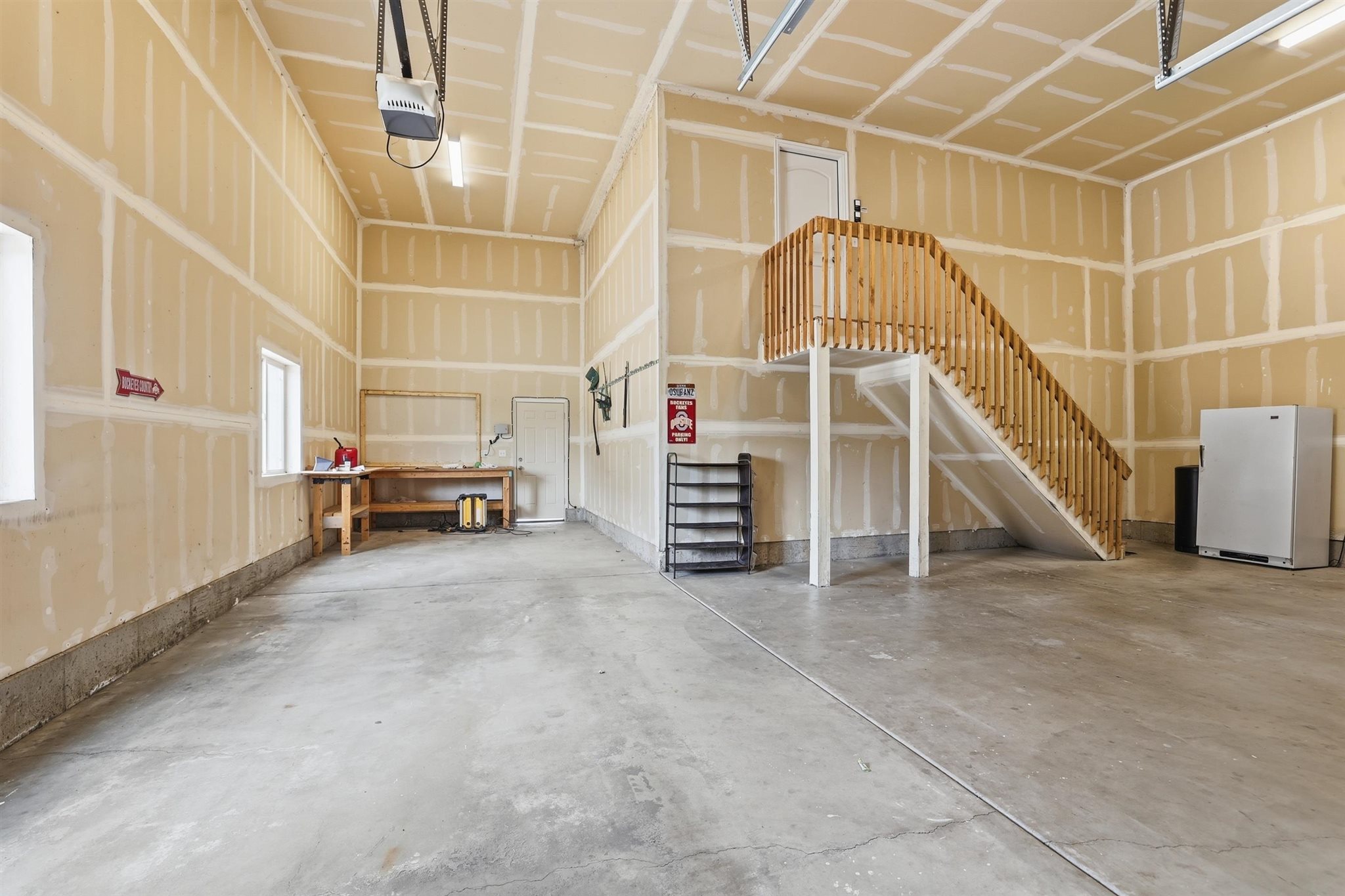 Spacious garage featuring a concrete floor, high ceilings, and exposed drywall