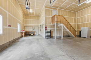 Spacious garage featuring a concrete floor, high ceilings, and exposed drywall