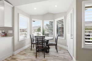 Bright dining nook featuring a bay window with plantation shutters, wood-finish flooring, recessed lighting, and a neutral color palette