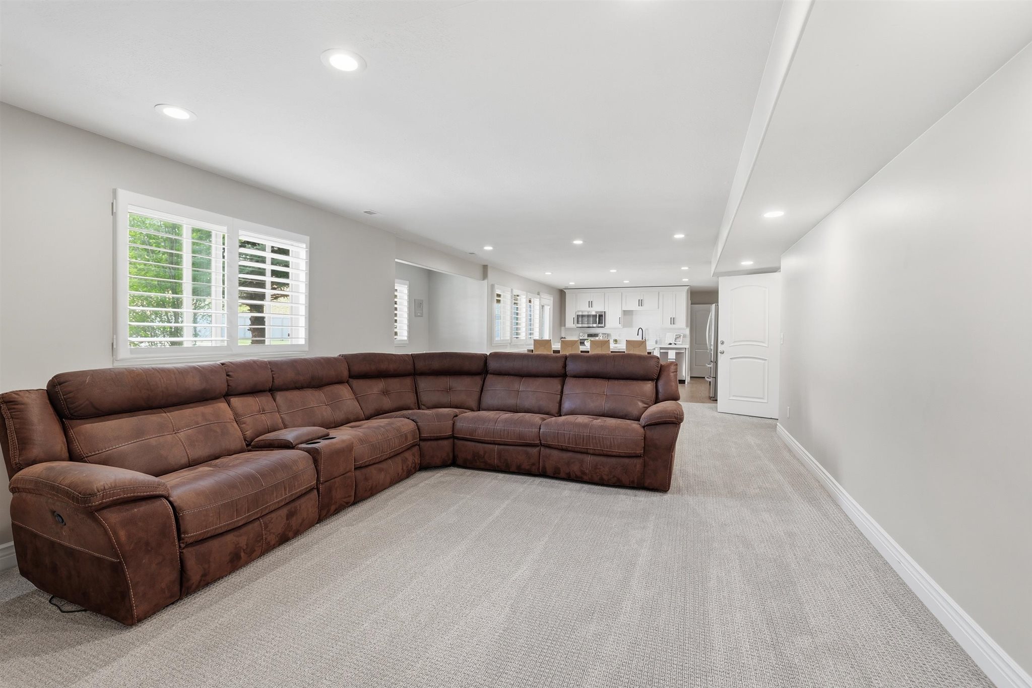 Spacious lower-level living area with recessed lighting, light gray carpet, and white baseboards