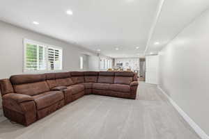 Spacious lower-level living area with recessed lighting, light gray carpet, and white baseboards