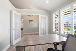 Office space featuring vaulted ceilings, recessed lighting, wood-finish flooring, and double French doors with frosted glass panels