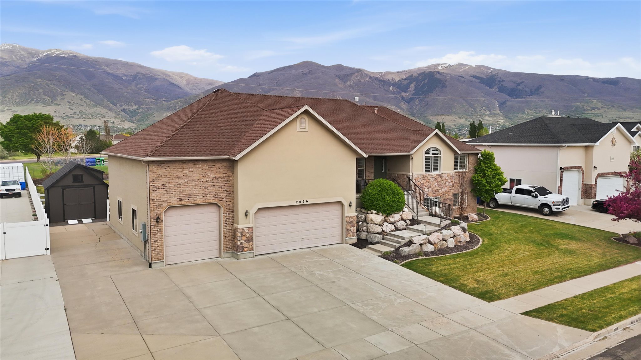Contemporary residence featuring a two-car garage, stucco and brick facade, and a tiered front yard with stone landscaping