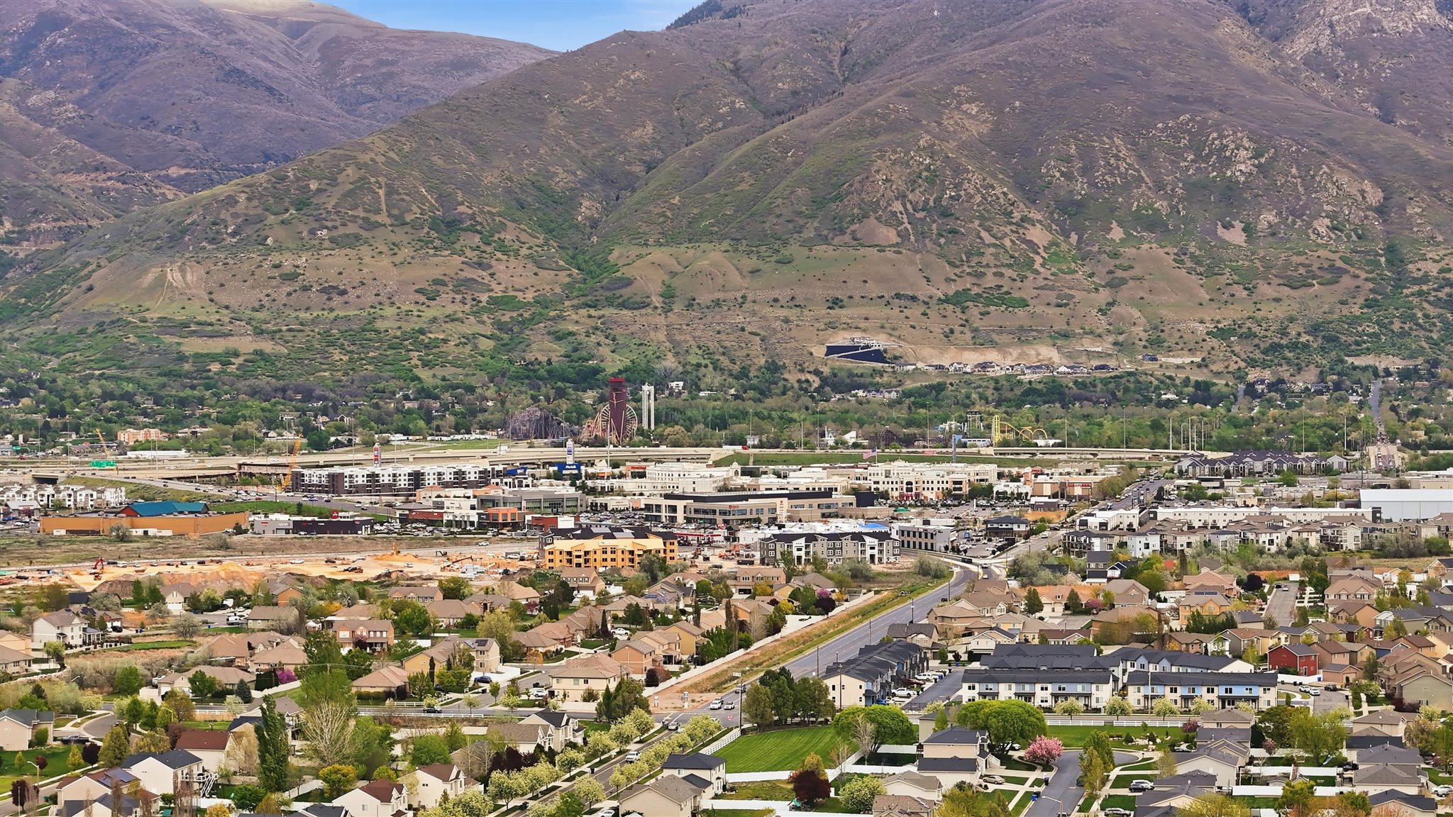 Expansive neighborhood with diverse residential architecture and commercial areas, set against a backdrop of prominent mountains