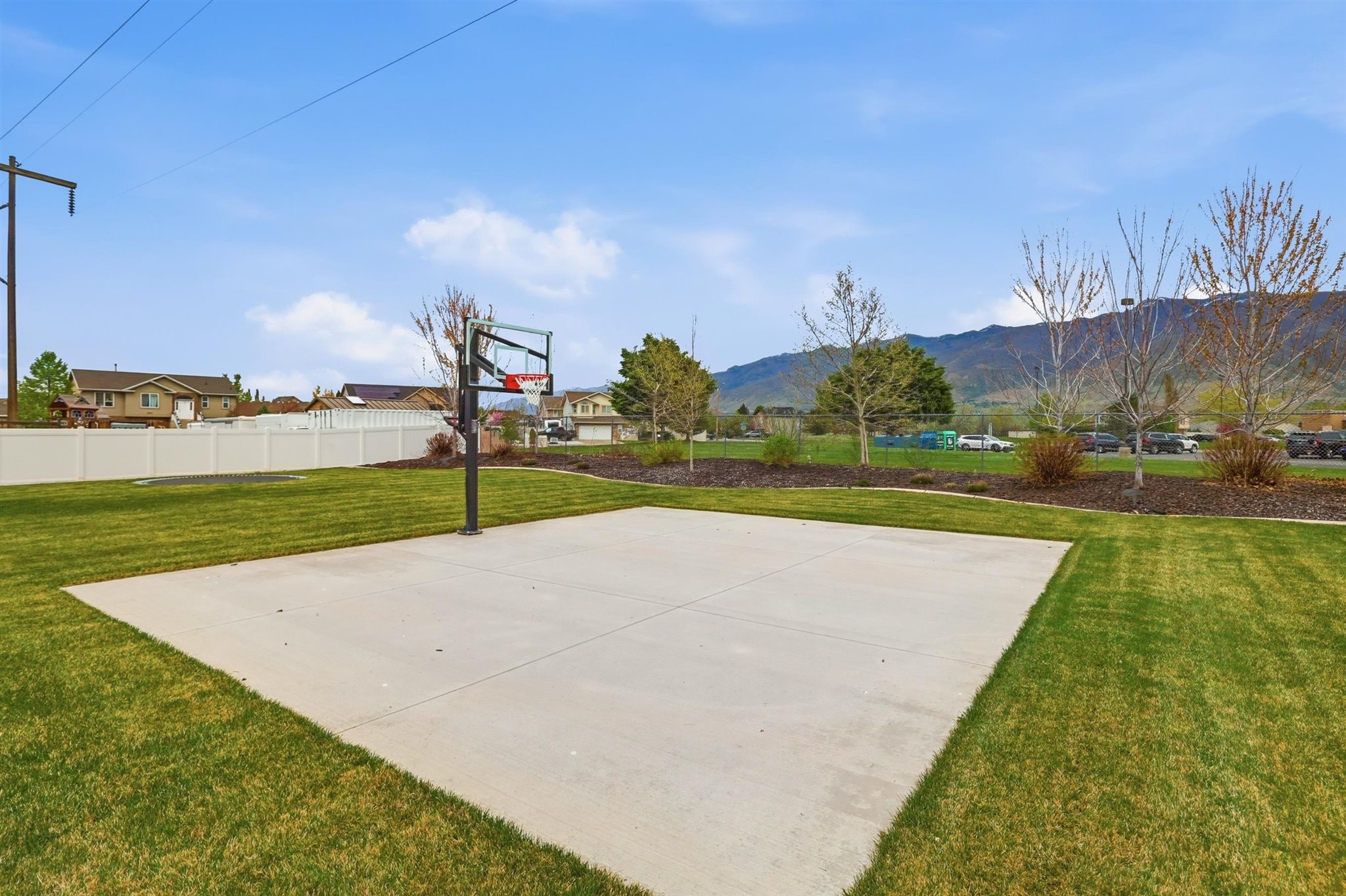 Recreational concrete pad with an adjustable basketball hoop, surrounded by green lawn
