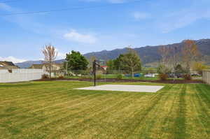 Expansive outdoor space featuring a large lawn area, a dedicated concrete pad, and a basketball hoop