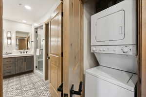 Bathroom featuring a patterned tile floor, a single vanity with a white countertop and gray cabinetry, a rectangular mirror, and wall-mounted sconces