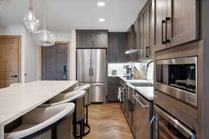 Modern kitchen featuring wood-finish cabinetry, stainless steel appliances, and a light-toned countertop