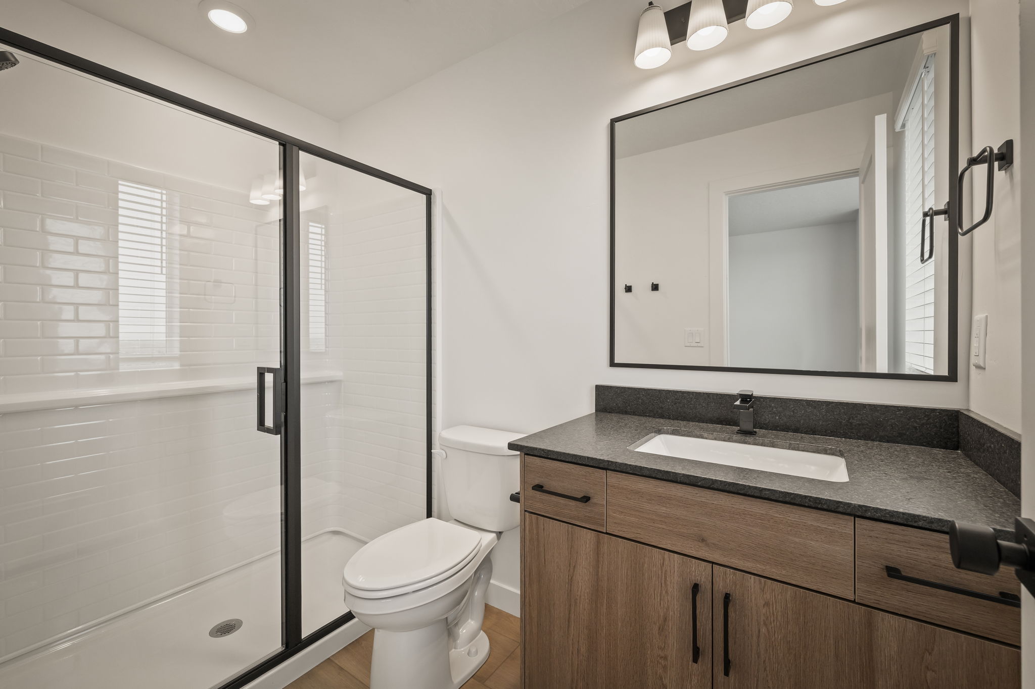 Modern bathroom featuring a walk-in shower with subway tile surround and black-framed glass enclosure