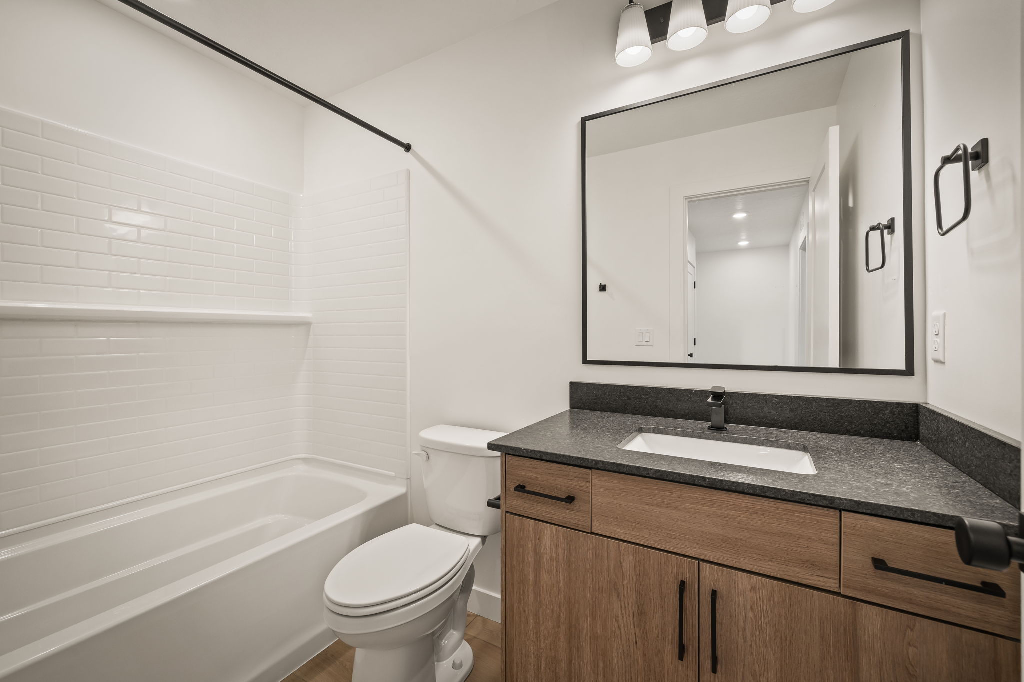 Bathroom featuring a modern vanity with wood-finish cabinetry, a rectangular undermount sink, and a dark countertop