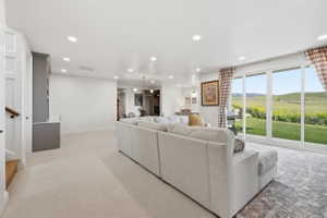 Spacious living area featuring light-toned carpeting and recessed lighting