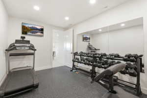 Dedicated exercise room featuring wall-to-wall mirrors, recessed lighting, and durable rubber flooring