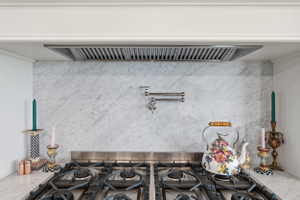 Professional-grade gas range with vent hood and a pot filler faucet