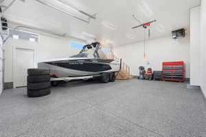 Spacious garage featuring a durable speckled epoxy floor, overhead lighting, an exposed wood staircase, and an internal access door