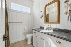 Bathroom vanity featuring a dark stone countertop with a built-in sink and brass-finish fixtures