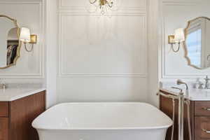 Freestanding soaking tub centered between two vanity stations