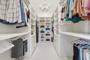 Custom closet system featuring extensive shelving, hanging rods, central storage tower, built-in drawers, and overhead chandelier lighting
