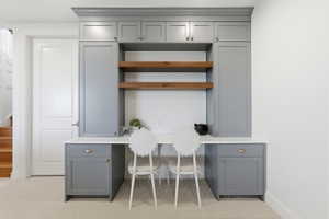 Built-in desk area featuring Portsmouth blue cabinetry, a light-toned countertop, and natural wood-finish open shelving