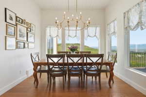 Spacious dining area featuring engineered hardwood flooring, a vaulted ceiling with tongue-and-groove paneling, and a custom chandelier