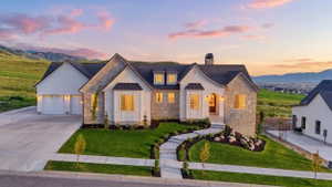 View of front of home with natural stone accents and fully landscaped yard