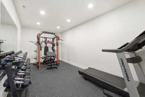 Dedicated fitness space featuring rubberized flooring, recessed lighting, and a full-wall mirror