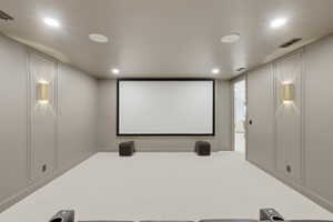 Dedicated media room featuring a large projection screen, recessed ceiling lighting, and integrated ceiling speakers
