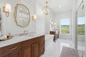 Primary bathroom featuring a freestanding tub, glass-enclosed shower, dual wood-finish vanities with marble countertops, and patterned tile flooring