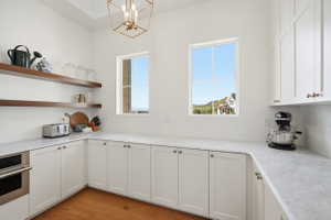 Pantry with wood shelving, microwave and cabinetry with marble countertops