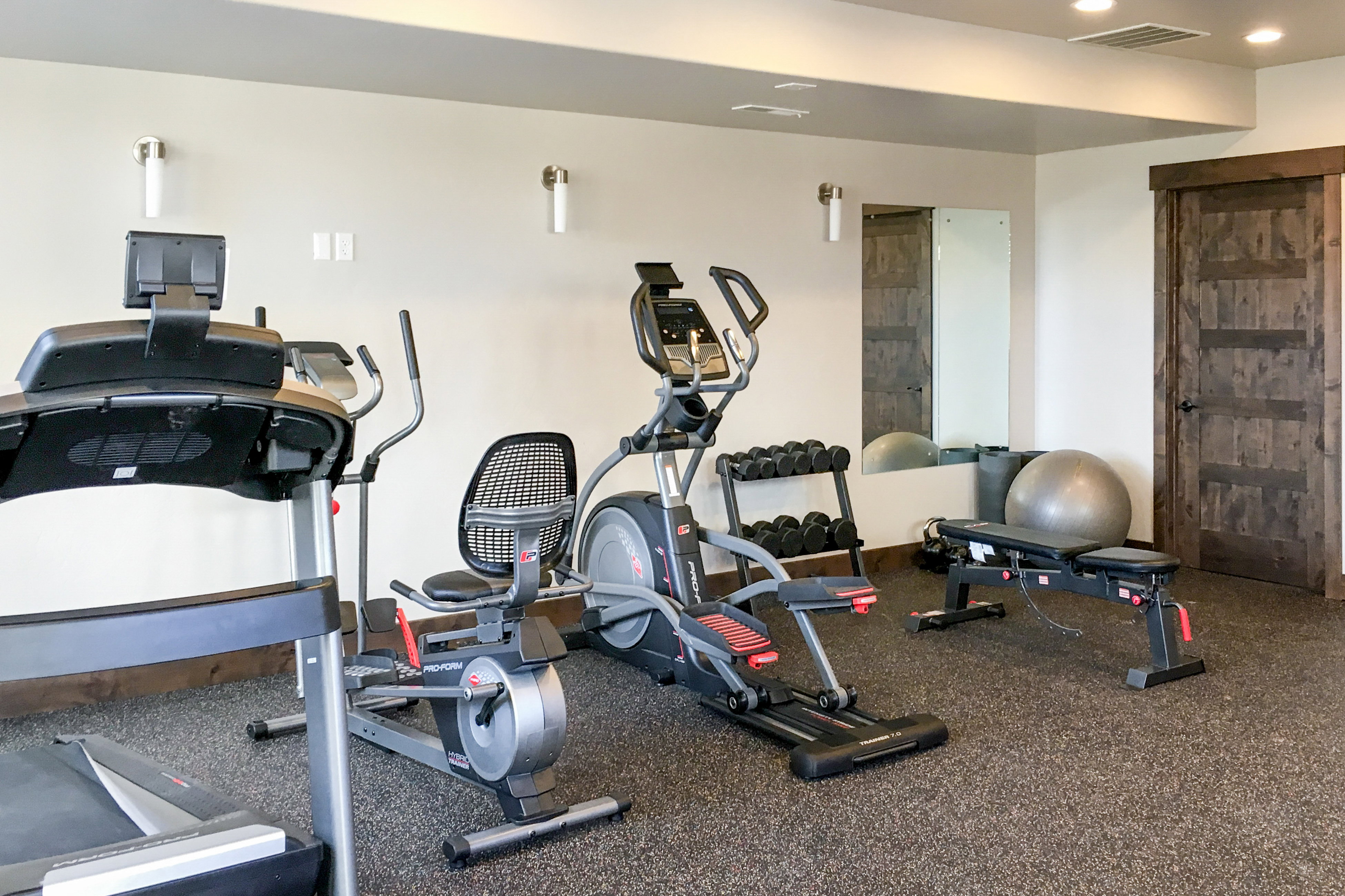 Dedicated exercise space featuring specialized resilient flooring, recessed ceiling lighting, and wall-mounted sconces