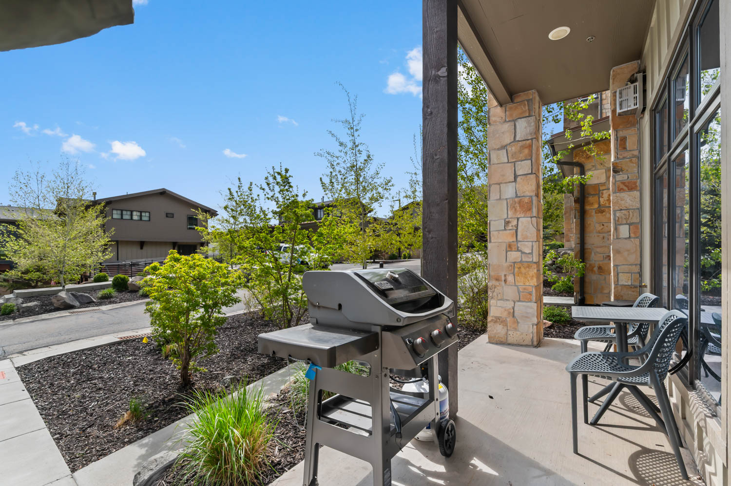 Covered patio featuring stone veneer accents, a dark wood support column, and large windows