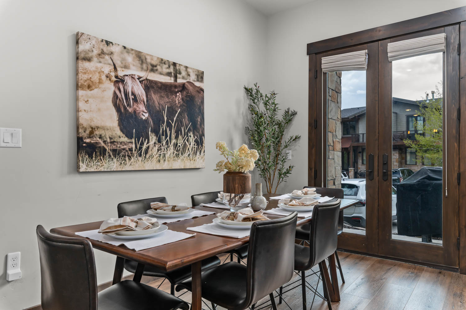 Dining area featuring rich wood-finish flooring, light-toned wall paint, and double French doors with dark wood frames