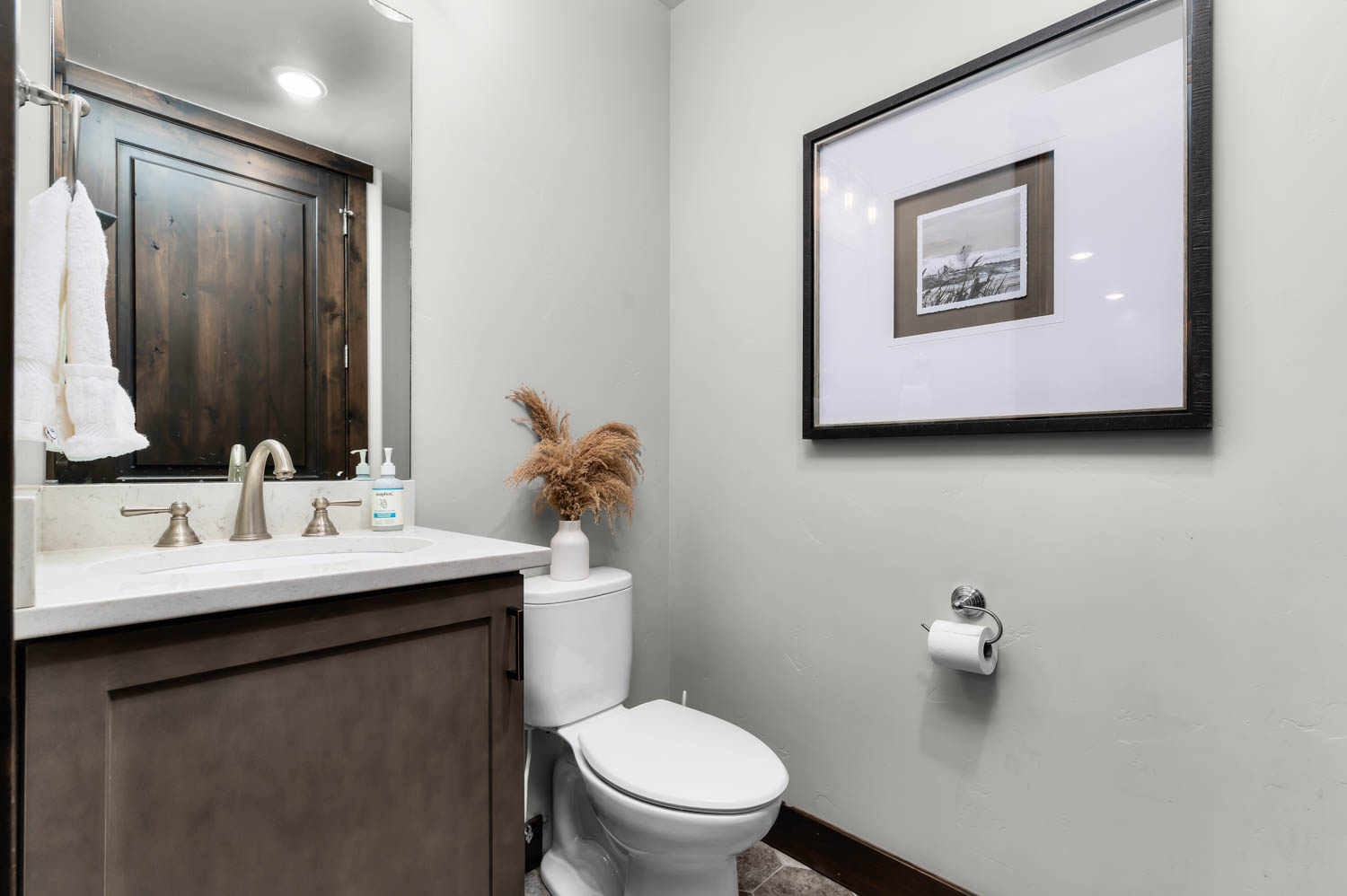 Powder room featuring a single vanity with stone countertop, undermount sink, and brushed nickel faucet