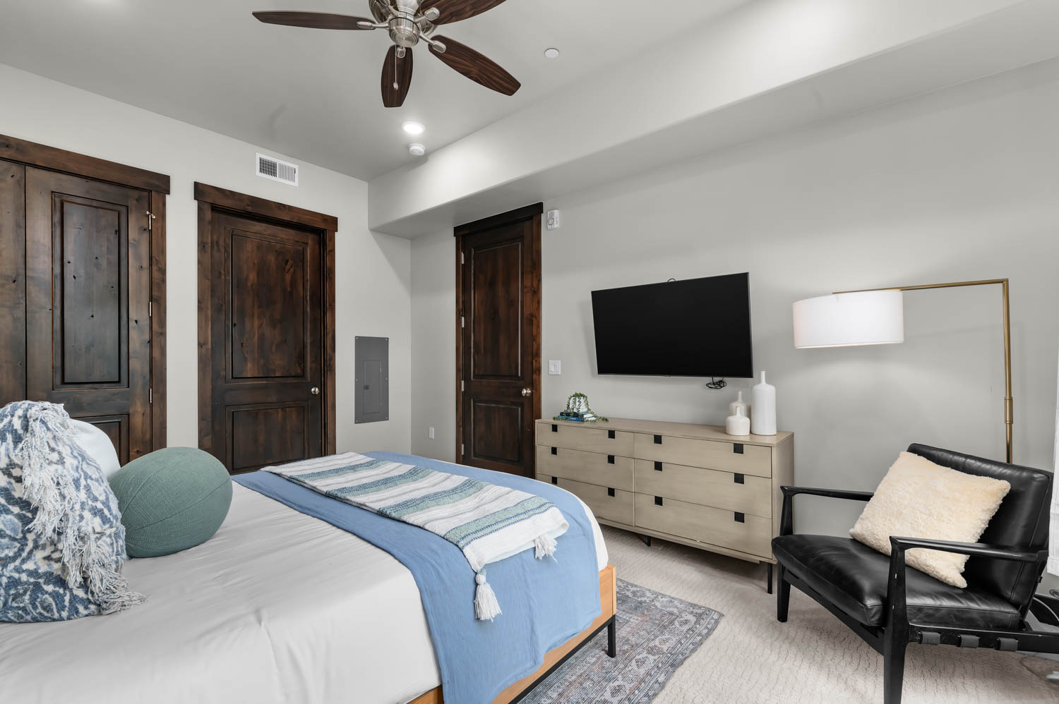 Recessed ceiling lights illuminate a ceiling fan with wood-finish blades
