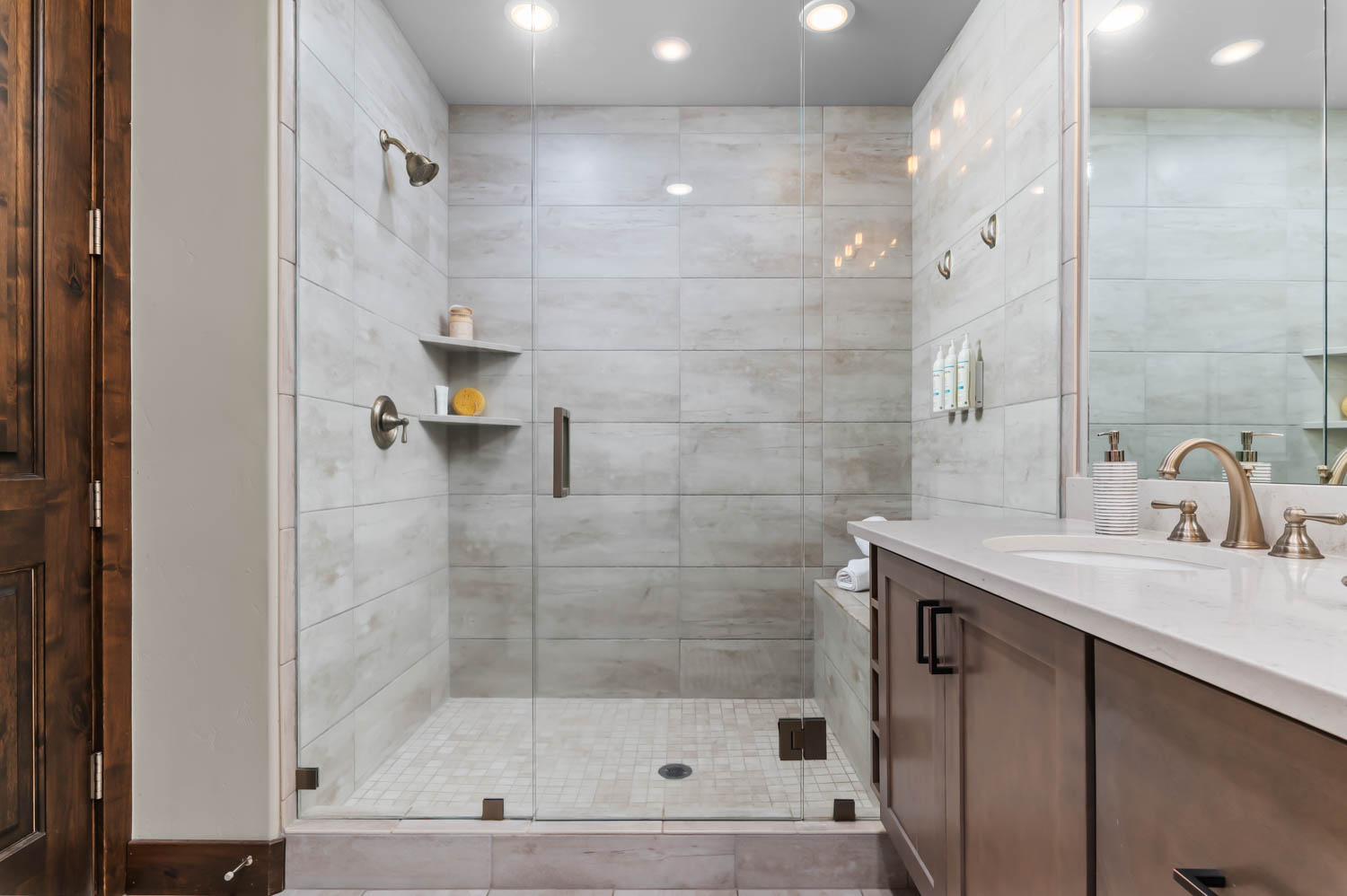 Walk-in shower featuring glass enclosure, light-toned tile walls, and a built-in bench
