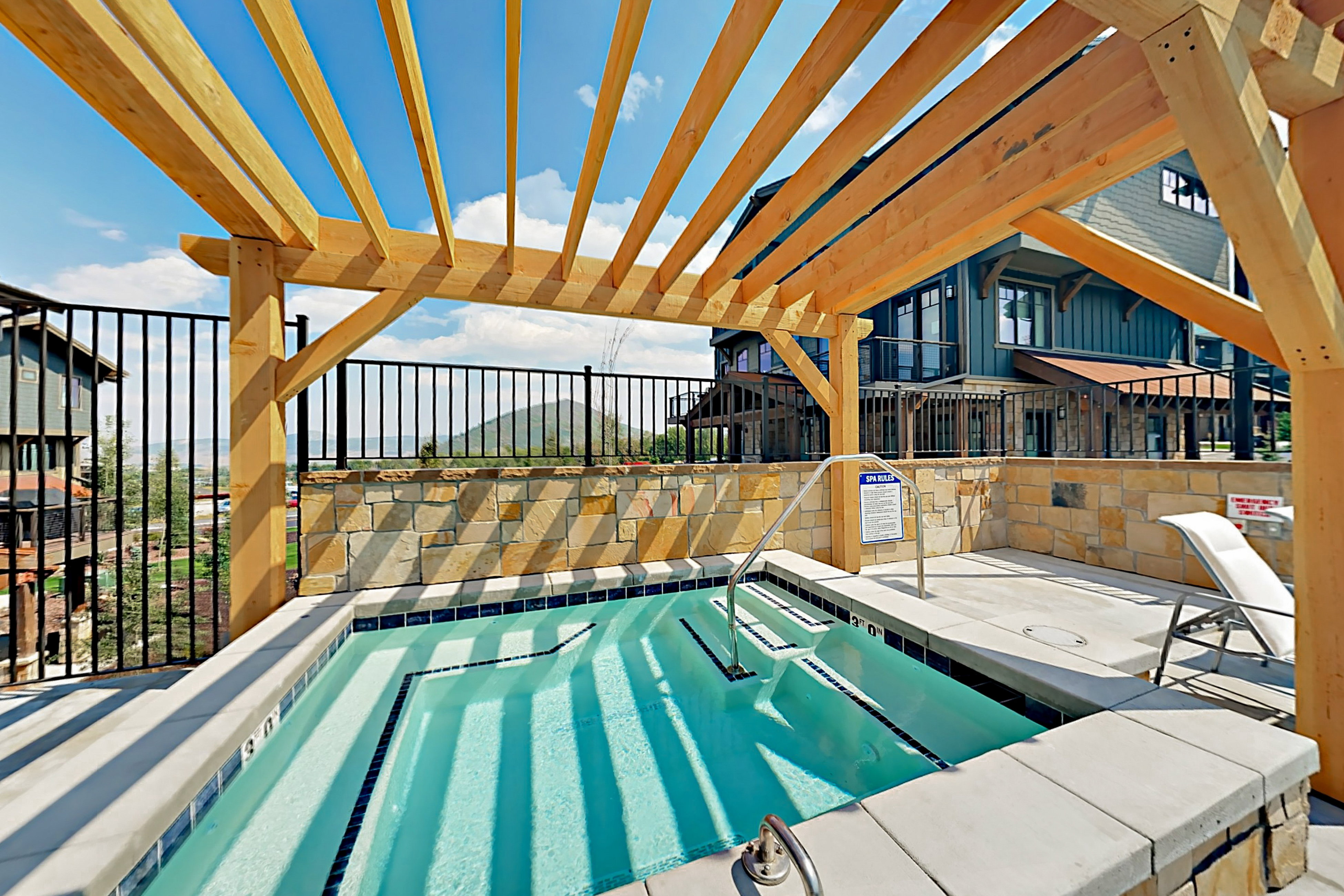 Outdoor spa with integrated steps, surrounded by light-colored coping and a stone-clad perimeter