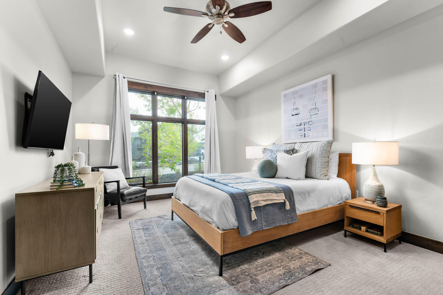 Bedroom featuring a wide window with dark wood framing, a tray ceiling, and recessed lighting
