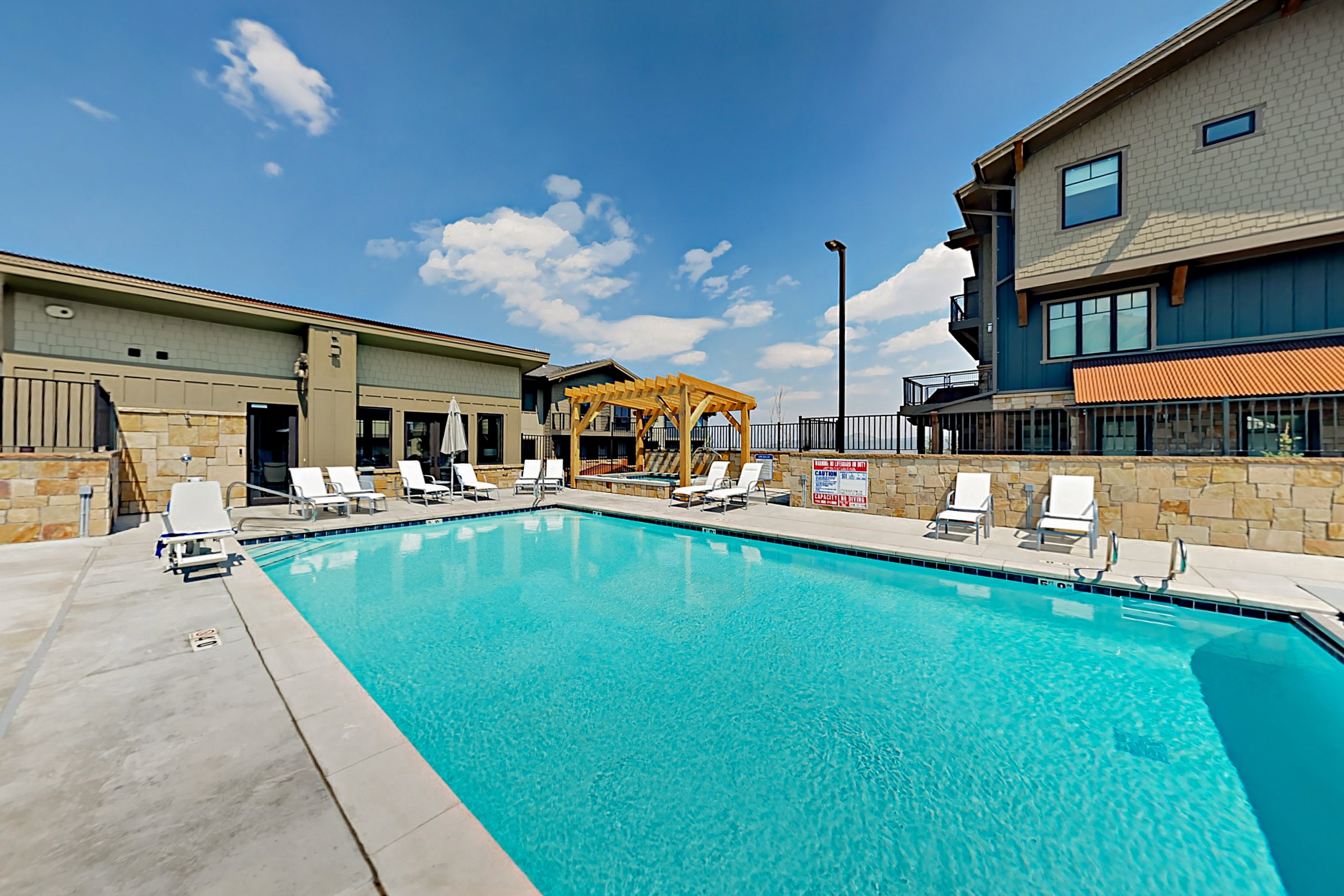 Outdoor swimming pool with integrated steps, surrounded by a concrete deck and stone retaining walls