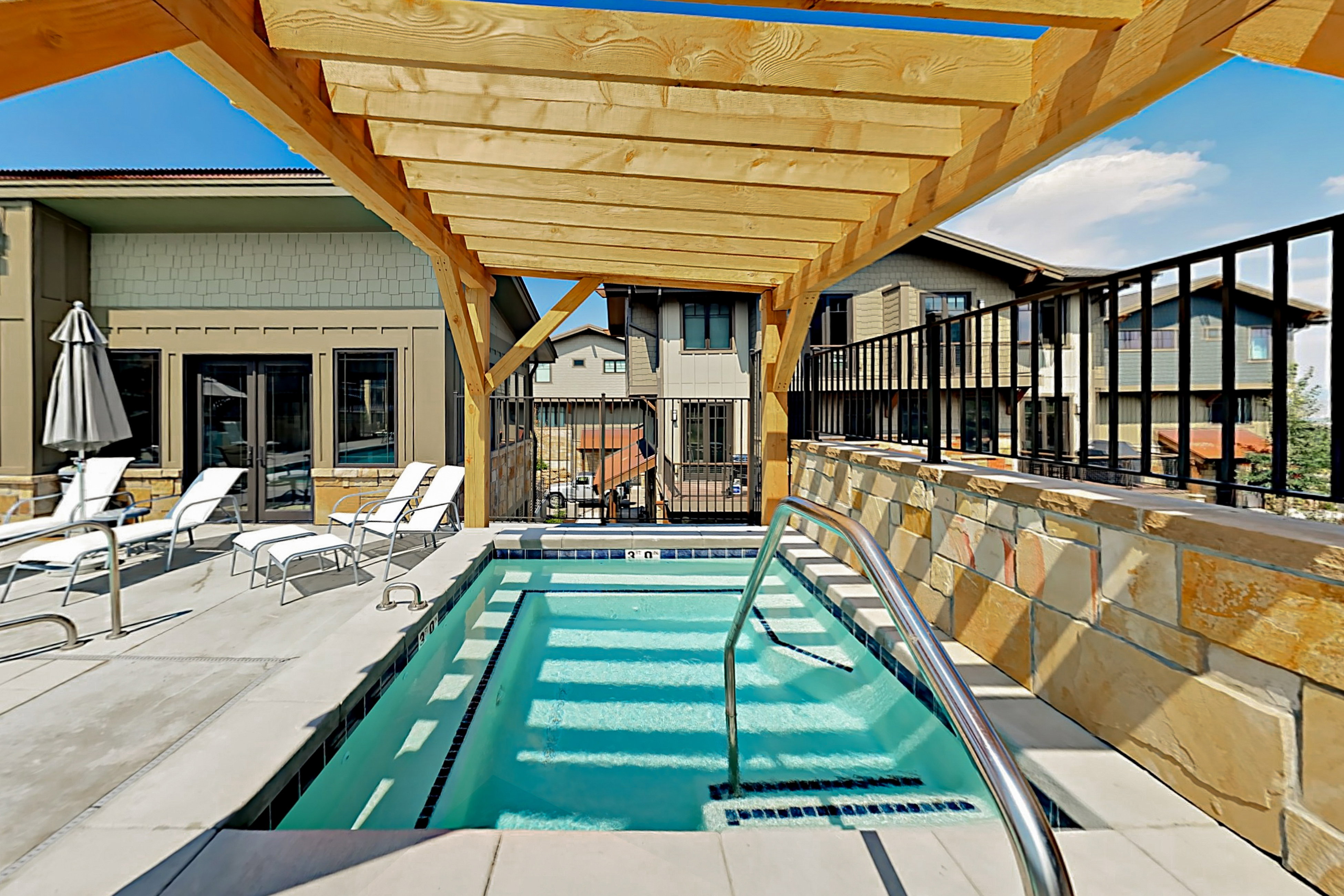 Outdoor spa with integrated steps and a stainless steel grab bar